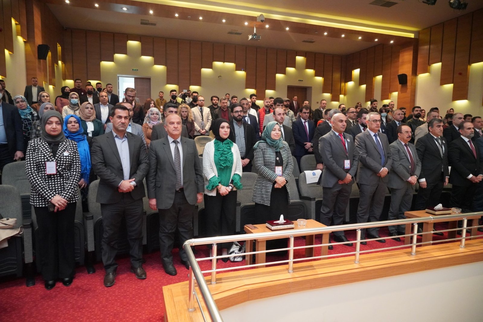 Audience standing in the conference hall at the opening