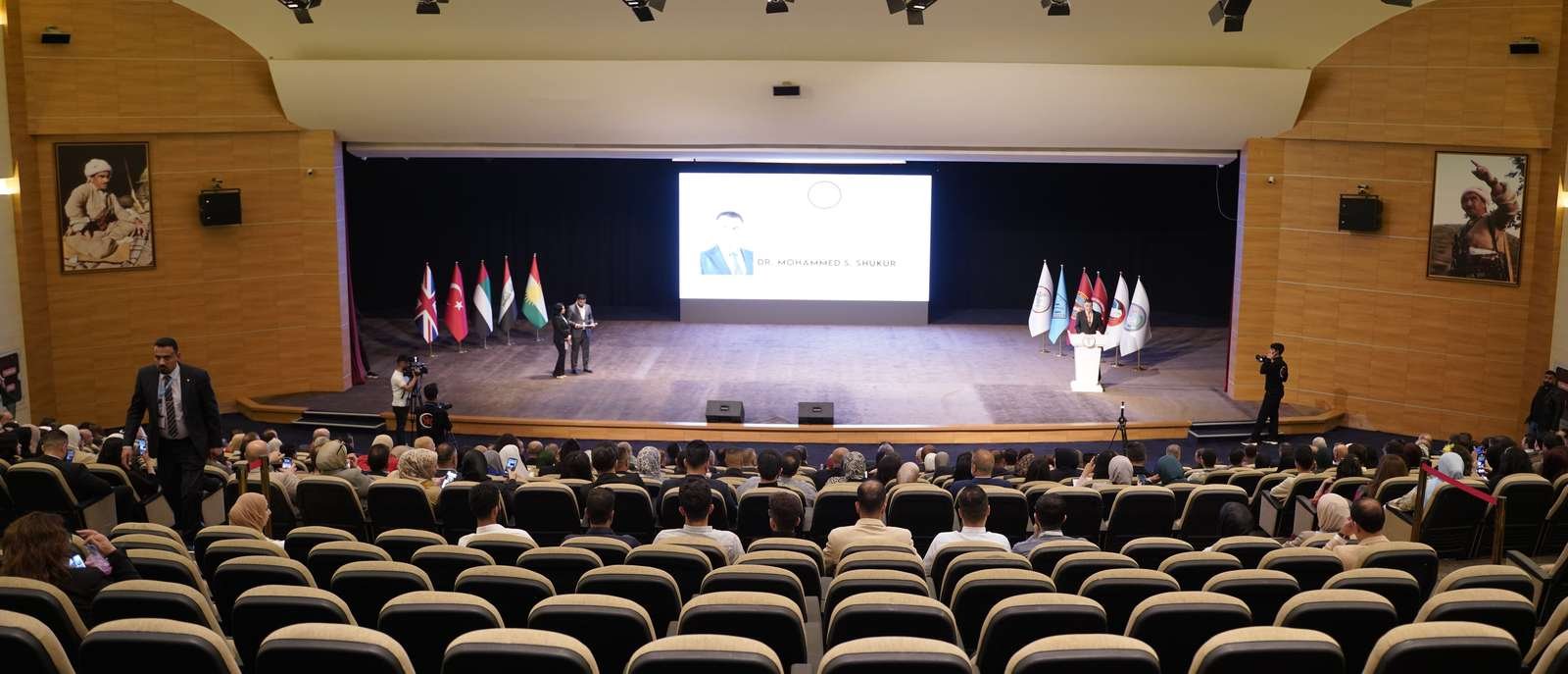 Convention Center hall during the conference, stage with flags and screen
